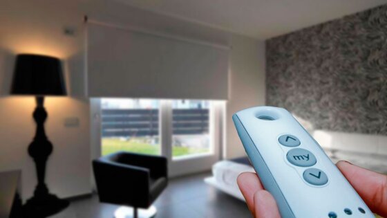 Cortina enrollable automatizada operada con control remoto, instalada en ambiente moderno, destacando confort, tecnología y diseño inteligente